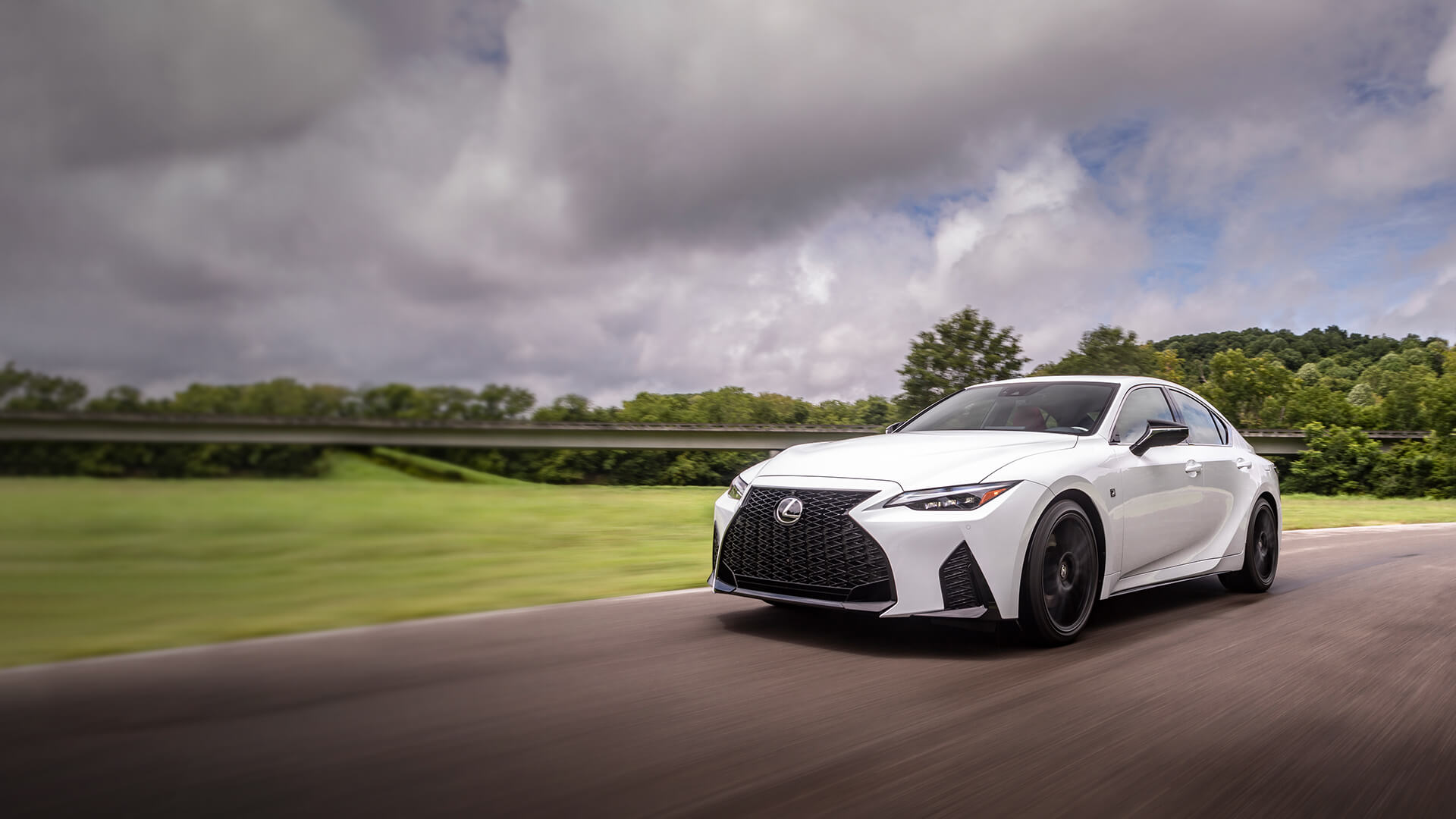 White Lexus IS being driven on the road.