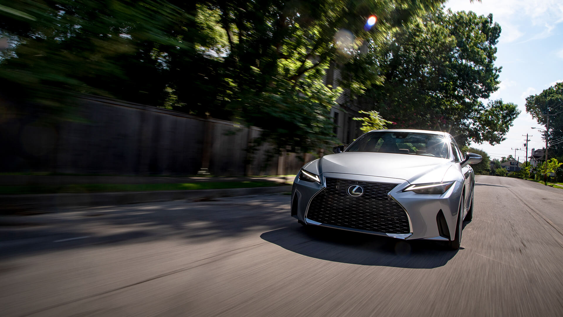 Silver Lexus IS being driven on the road.
