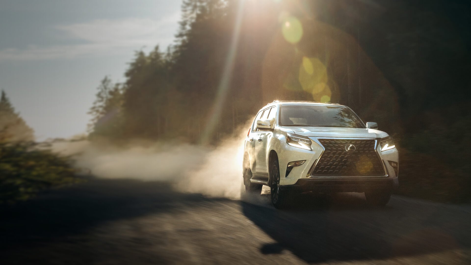 White Lexus GX being driven on a dirt road.