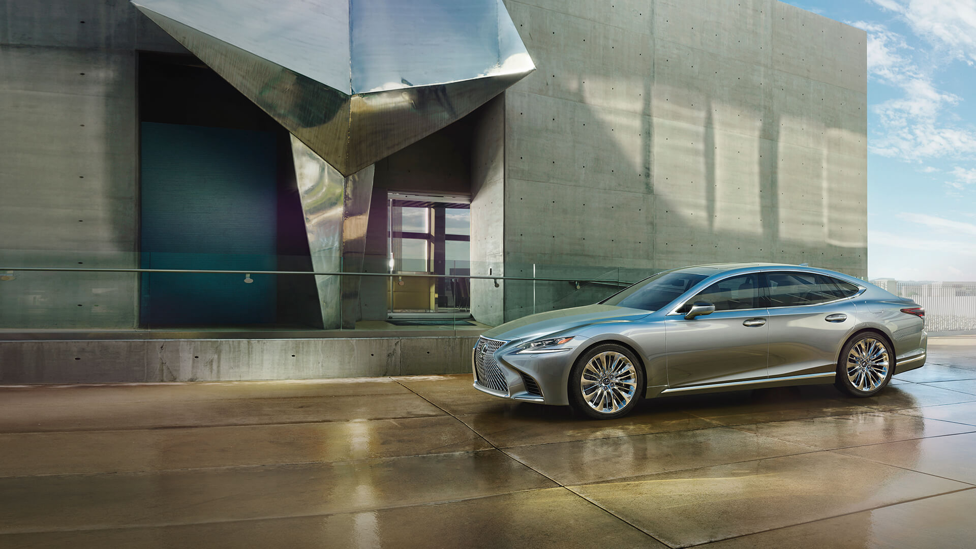 Silver Lexus LS in front of a grey, concrete building.